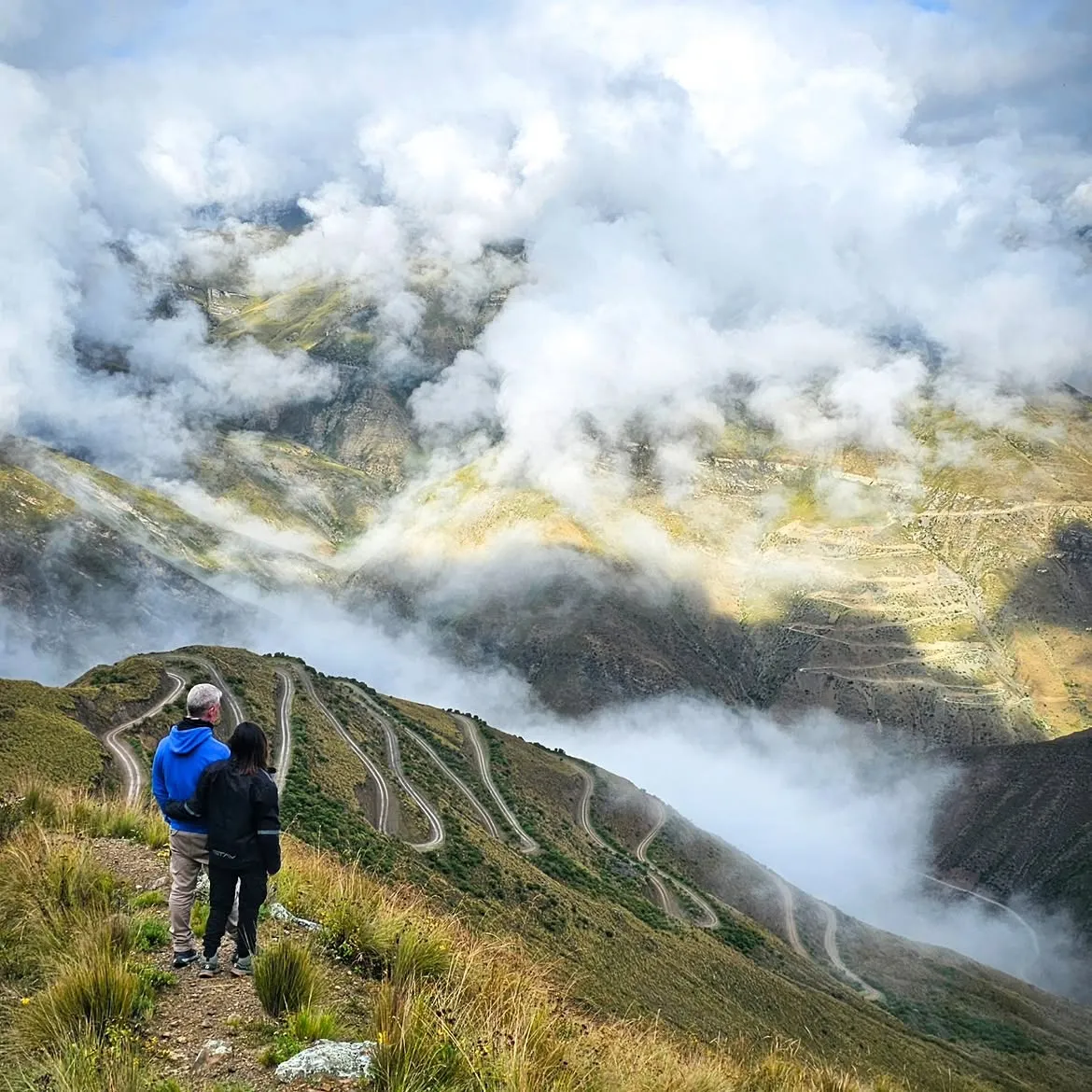 Pareja de viajeros mirando las curvas de la cuesta de Caspalá entre nubes, primer día de la travesía