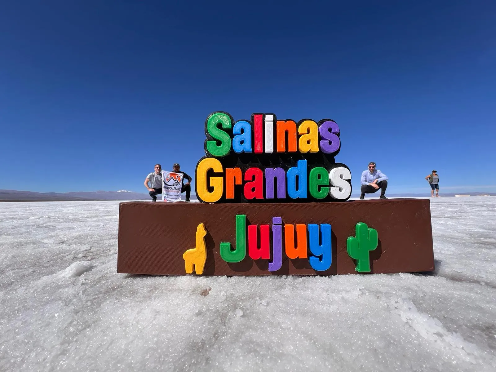 Viajeros junto al cartel de Salinas Grandes Jujuy sobre el salar