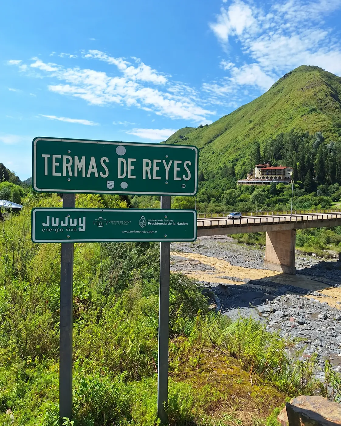 Cartel de Termas de Reyes con el hotel termal y los cerros verdes al fondo