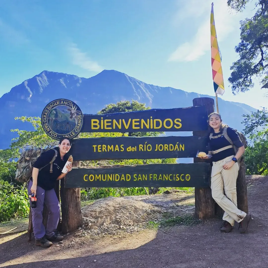 Viajeras junto al cartel de bienvenida a las Termas del Río Jordán, comunidad San Francisco
