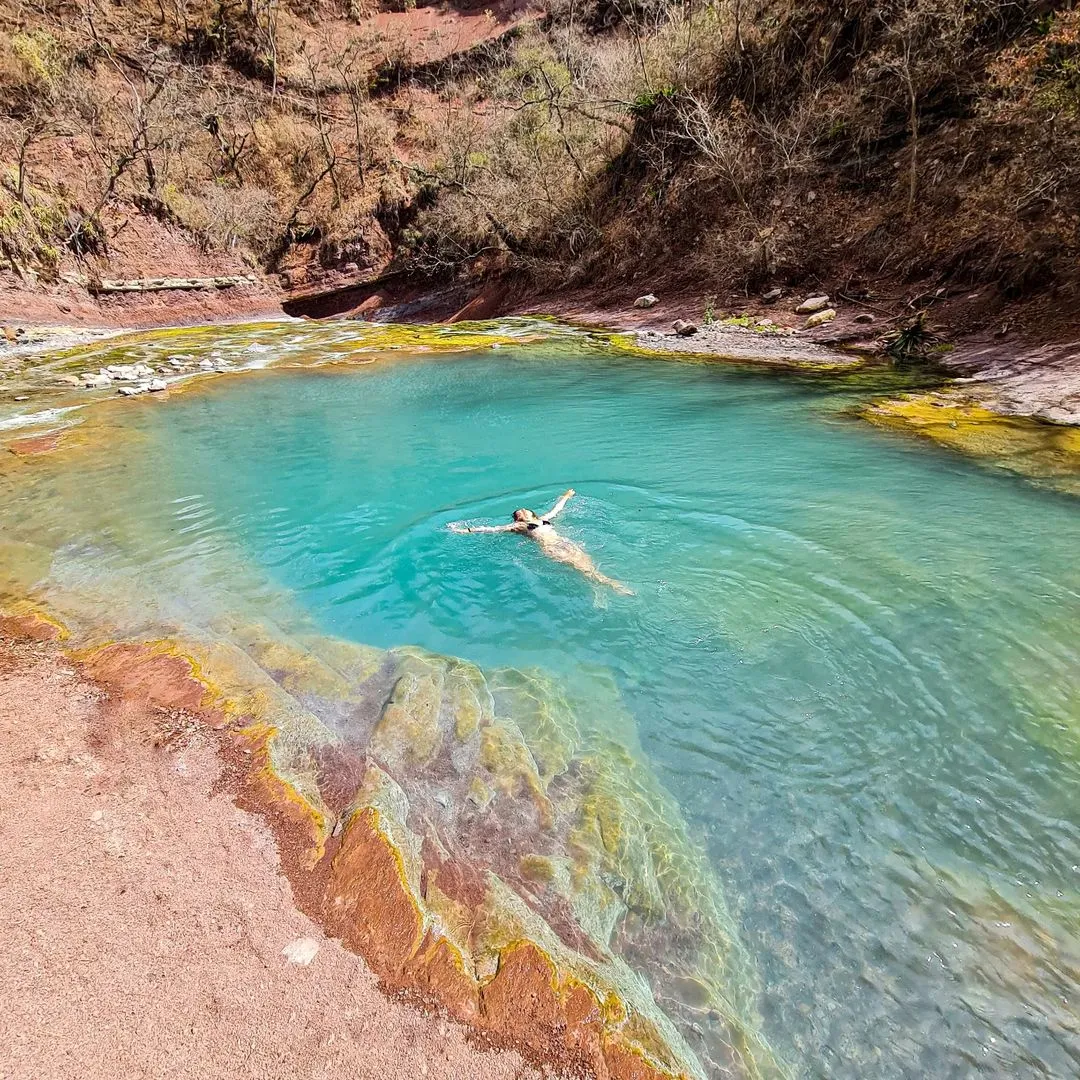 Viajera flotando en la pileta turquesa de las Termas del Río Jordán, en las Yungas de Jujuy